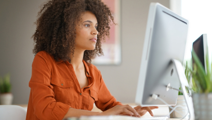 Woman sitting behind a desktop computer screen.