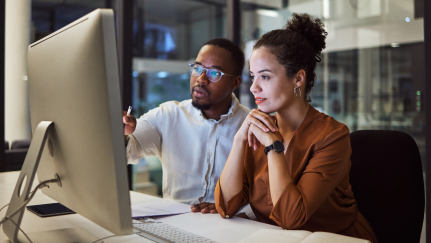 Two individuals looking at a desktop computer screen.